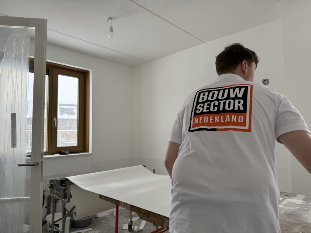 Behanger van Bouwsector Nederland werkt alleen aan de plaktafel in een lege kamer
