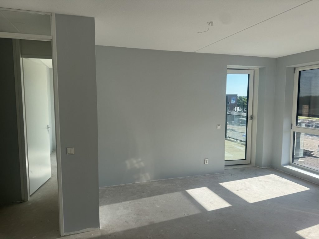 Grijze wand in een lichte kamer waar het zonlicht schuin binnenvalt