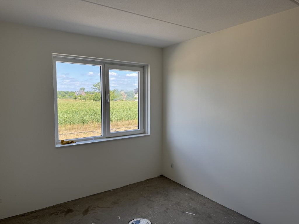 Lege kamer met lichte wanden en een raam, klaar om op te meten voor behang