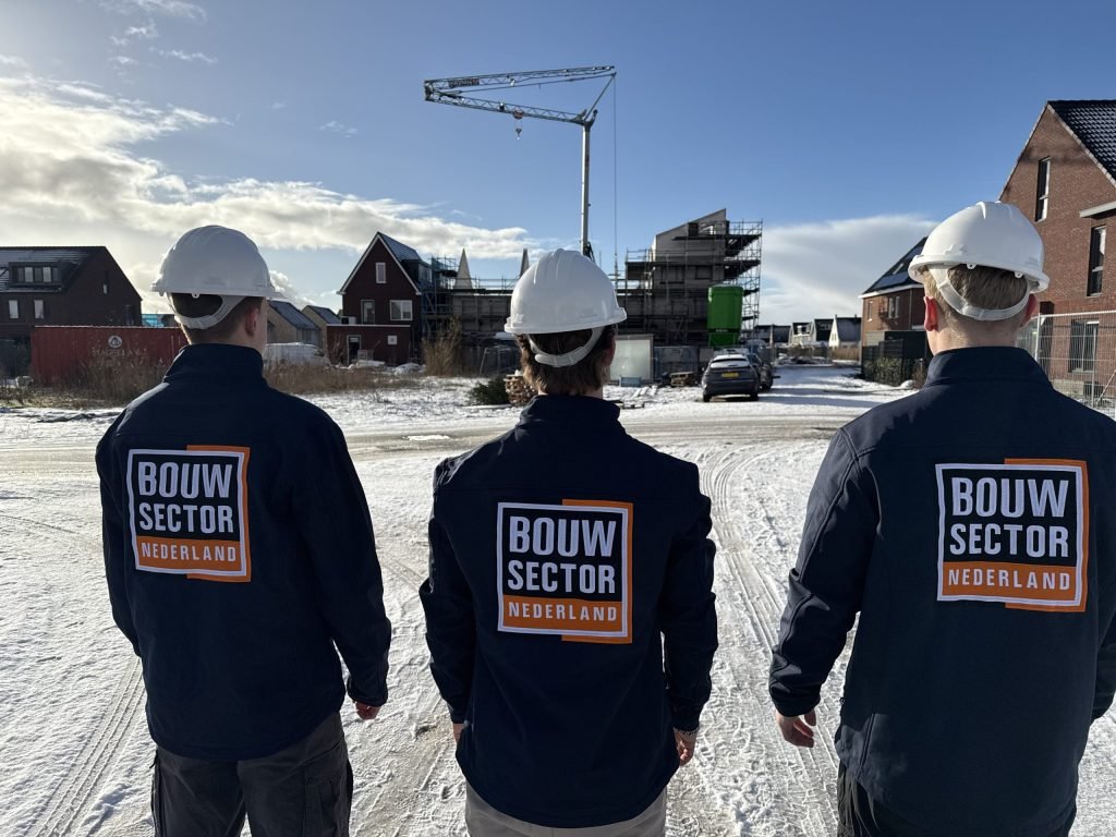 Drie vakmensen van Bouwsector Nederland met witte helm voor woningen in aanbouw in de sneeuw